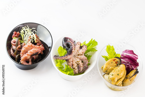 Mini canapes with seafood and vegetables and herbs and in plastic utensils isolated on white background. 