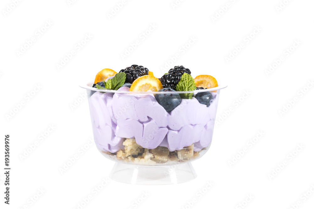 Creamy cream dessert in a plastic cup decorated with berries on a white background. 