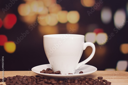cup of coffee on wooden table with defocus bokeh of coffee shop background. Image with soft focus and blurred background.