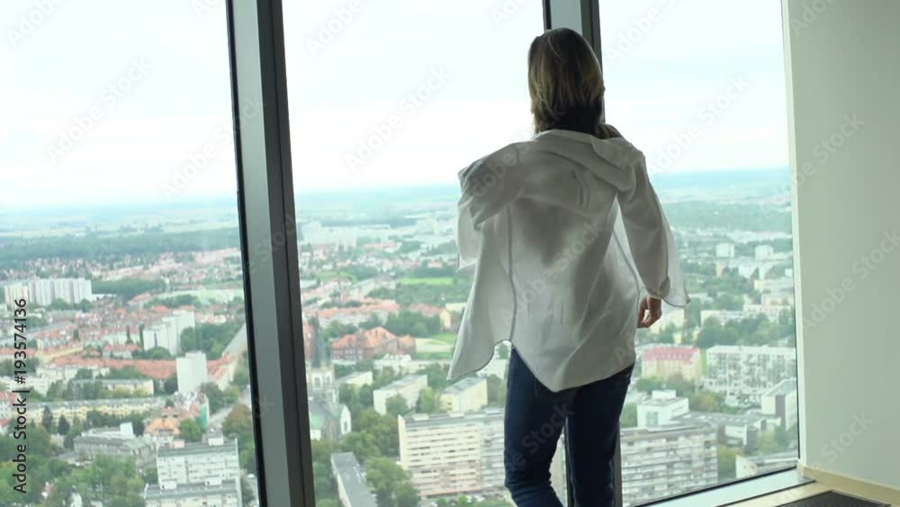 Young woman putting on white shirt by window
Young woman putting on white shirt by window