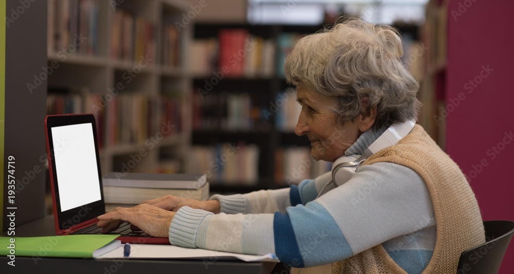 Senior woman using laptop in library Senior woman using laptop in library
