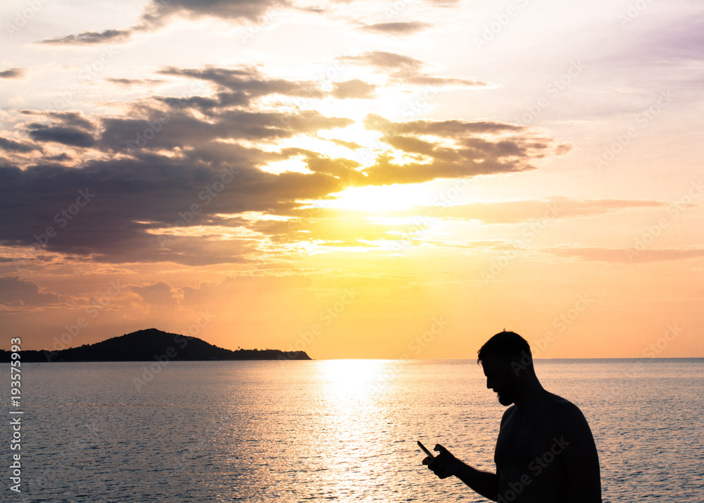 Man holding phone on sunset and sea background