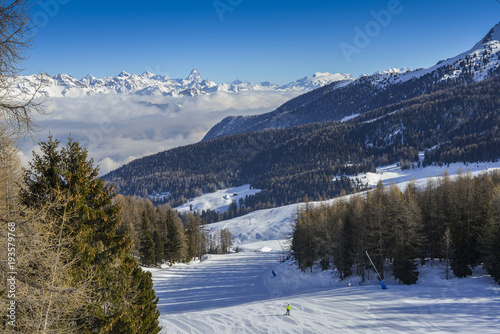 Panoramic view of wide and groomed ski piste in resort of Pila in Valle d'Aosta, Italy during winter