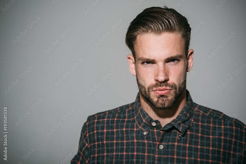 Portrait of serious and confident handsome bearded man in checkered shirt. Isolated on grey background. Copy space area for advertising, text or slogan. Portrait of serious and confident handsome bearded man in checkered shirt. Isolated on grey background. Copy space area for advertising, text or slogan.