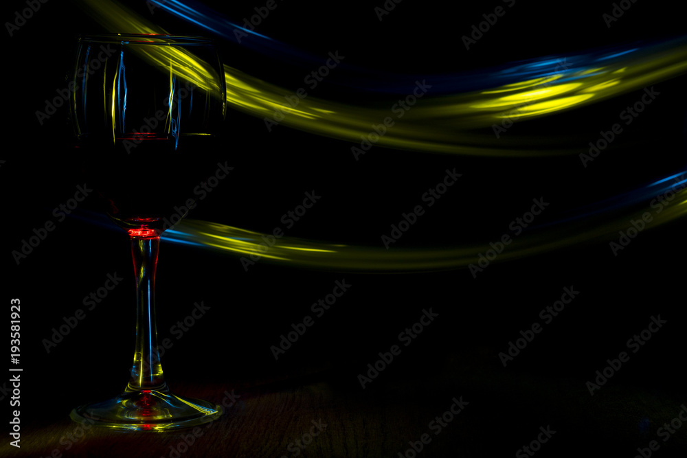 A glass of red wine in night club. Blue and yellow blurred bands.
