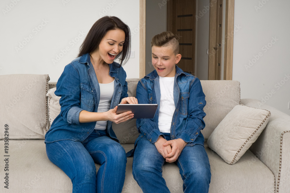 Happy family sitting on sofa and using digital tablet at home Happy family sitting on sofa and using digital tablet at home
