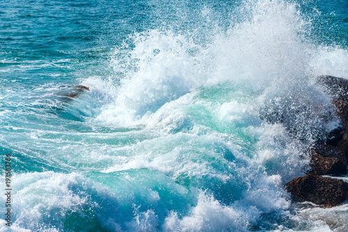 Beautiful blue wave in tropical ocean. Turquoise wave barrel crashing on rocks. Close up.
