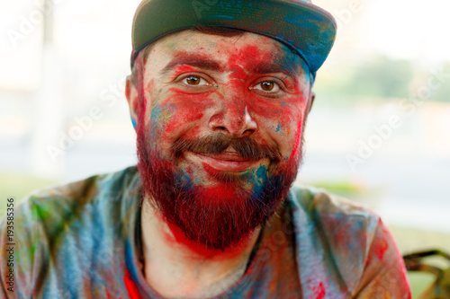 Young man smeared with colours plays Holi photo