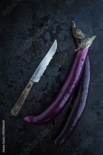 Fingerauberginen mit einem Messer auf einem dunklen Metalluntergrund photo