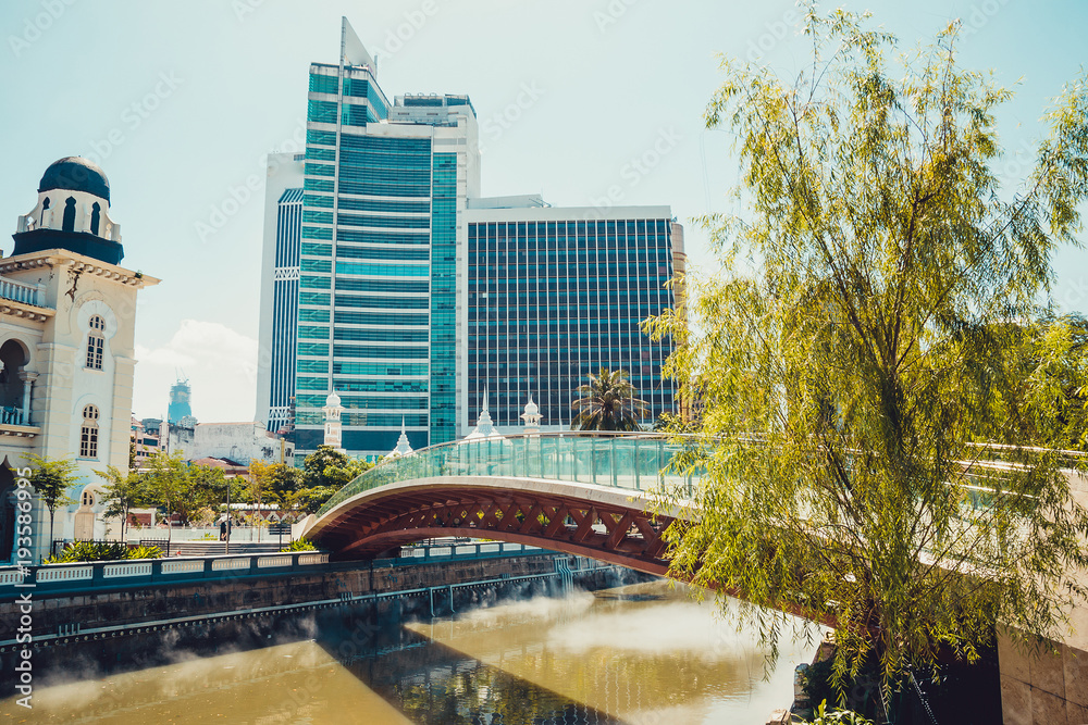 Fototapeta premium Kuala Lumpur cityscape. Modern and historic architecture. Travel to Malaysia. Mosque Masjid Jamek. City tour. Tourism industry. Urban background. City centre. Bridge across river of life