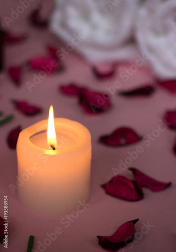 Scented candle and dry petals on pink background  wellness or spa background