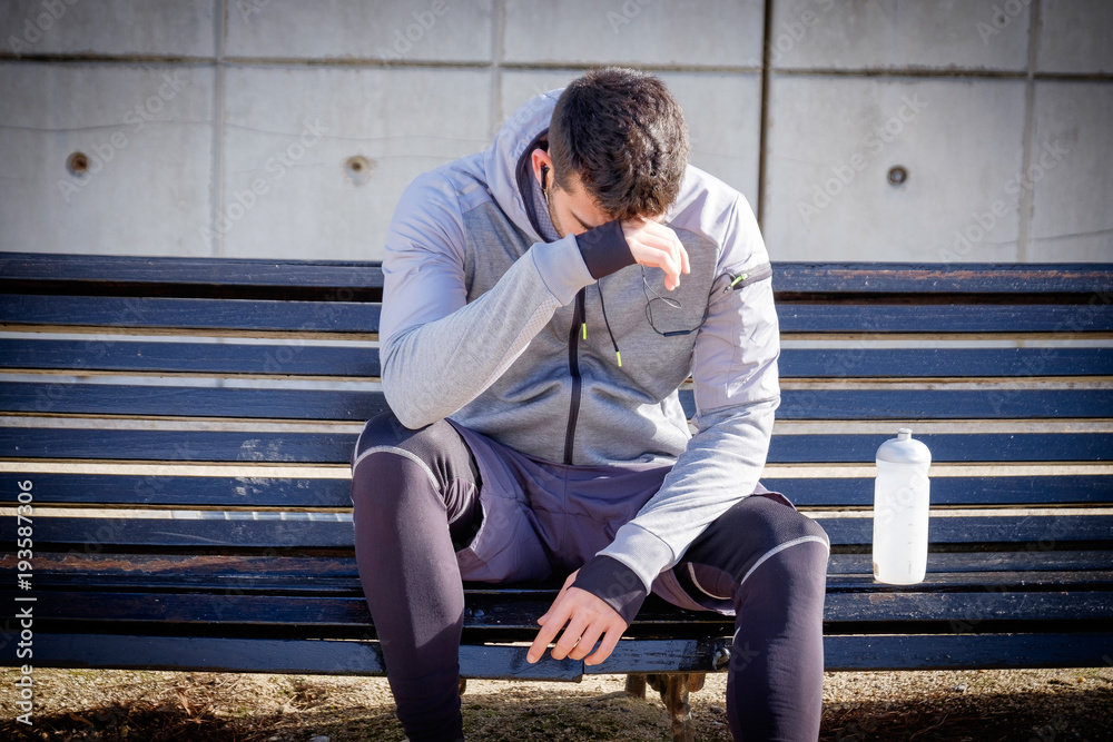 Young athlete man resting after running in a park Young athlete man resting after running in a park