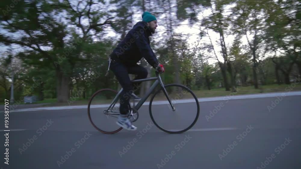 Man cycling at asphalt road in the green park at sunset in autumn time