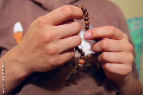 Female hands holding wooden rosary. Close up