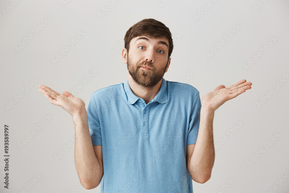 Portrait of uncertain good-looking caucasian bearded male, shrugging, standing with raised palms and pursed mouth, expressing hesitation over gray background. There is nothing that can be done Portrait of uncertain good-looking caucasian bearded male, shrugging, standing with raised palms and pursed mouth, expressing hesitation over gray background. There is nothing that can be done