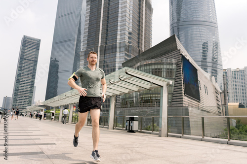 Young male runner running in Shanghai financial centre, Shanghai, China photo