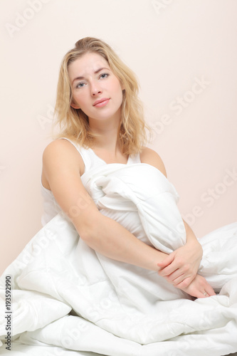 Smiling lady lies in bed indoors.