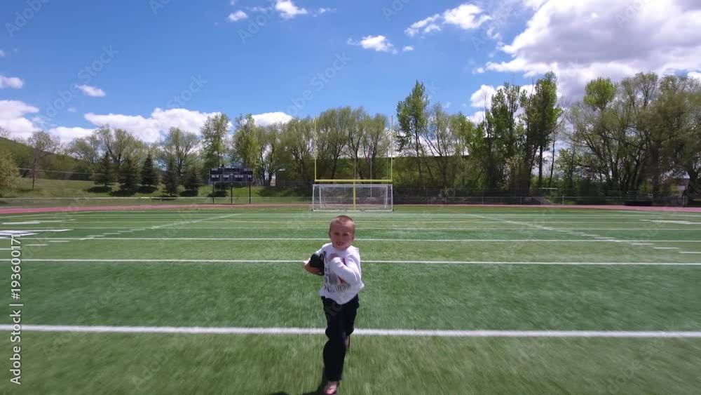 Seriouse young boy running with a football Seriouse young boy running with a football