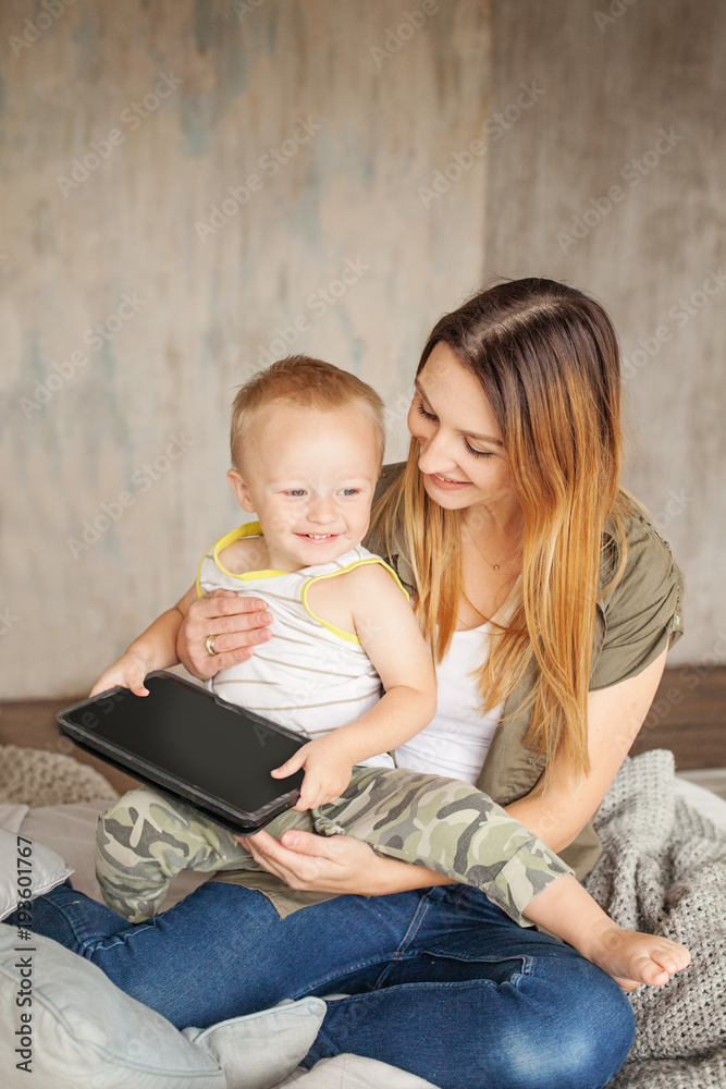 Happy Family at Home. Smiling mom and child boy with tablet. Pretty mother and her son playing and learning Happy Family at Home. Smiling mom and child boy with tablet. Pretty mother and her son playing and learning