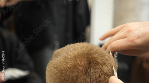 Young Man in Barber Shop Hair Care Service Concept. Man's hands doing a haircut for man at barber shop, close up