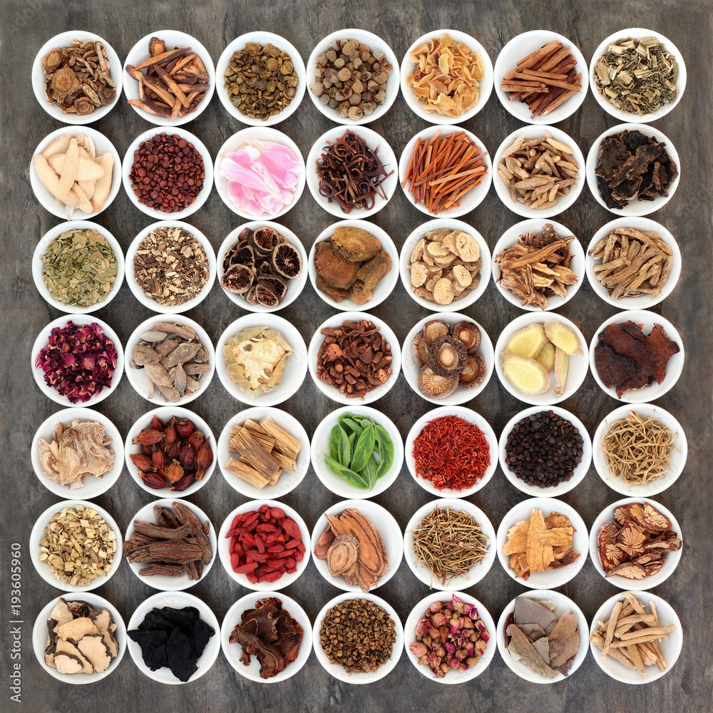 Traditional chinese medicine selection with a large collection of herbs in white porcelain bowls on marble background. Traditional chinese medicine selection with a large collection of herbs in white porcelain bowls on marble background.
