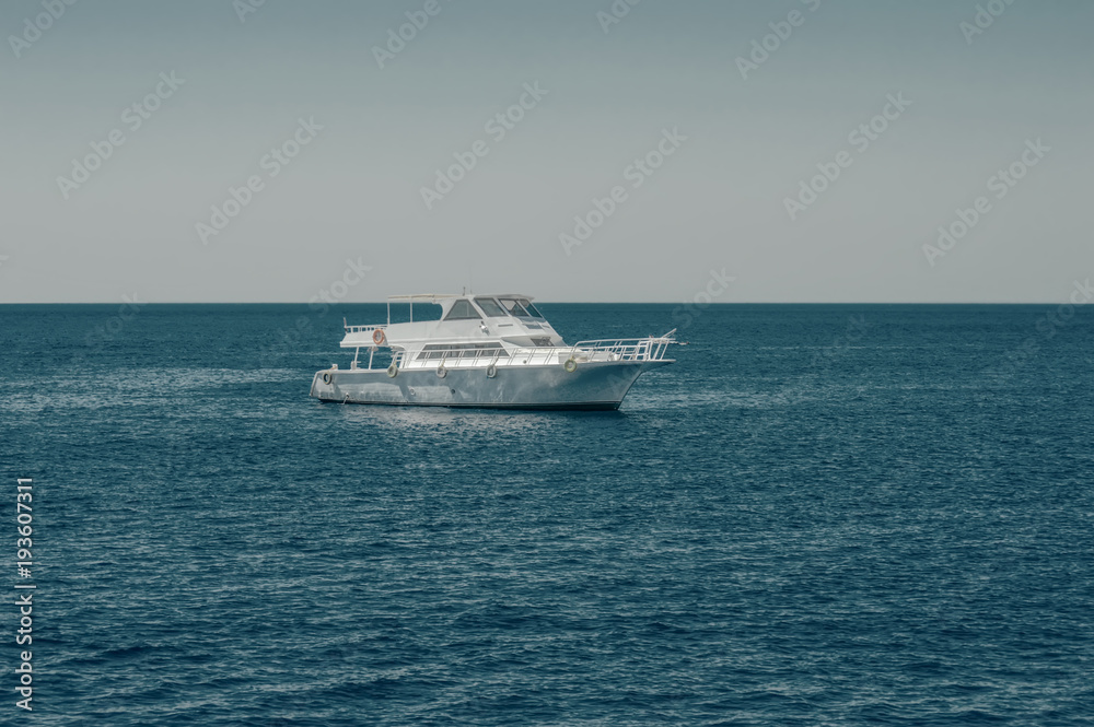 white boat, yacht in the calm sea, against the background of the horizon and sky without clouds, toning