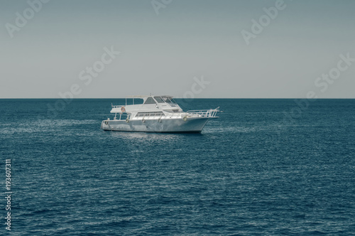 white boat, yacht in the calm sea, against the background of the horizon and sky without clouds, toning