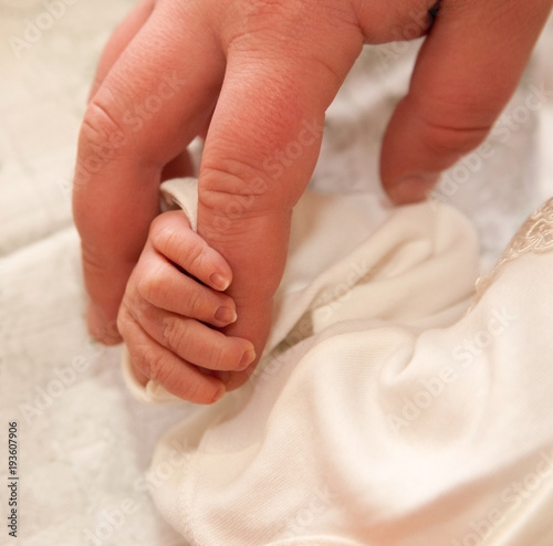 The baby clings to his father's finger