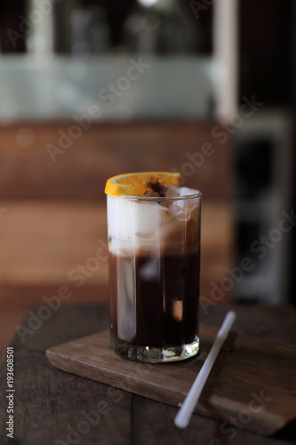 Ice black coffee with orange on wood background