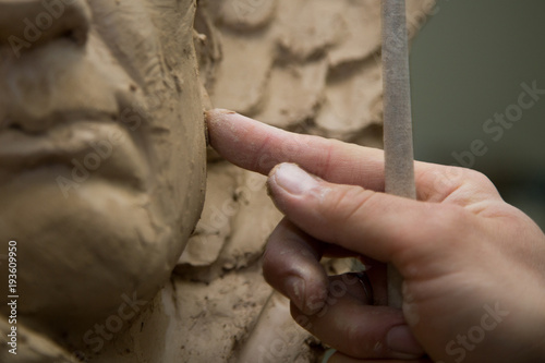 Sculptor artist creating a bust sculpture with clay