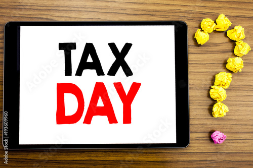 Writing text showing Tax Day. Business concept for Income taxation Refund written on tablet computer on the wooden background with question mark made of folded paper. photo