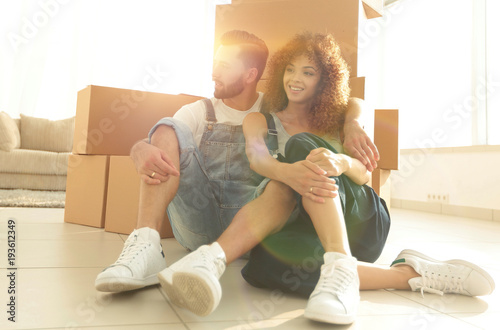 married couple sitting near cardboard boxes in a new apartment © ASDF