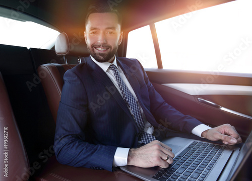 successful man working with laptop sitting in car