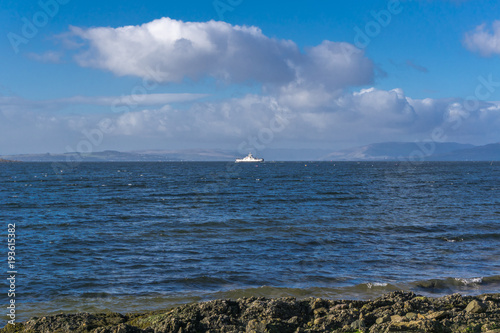 From the rocky shore at Largs is the River Clyde and in the distace is a car ferry and the Bute & Argyle Hills in the misty distance. A good tourism image. photo