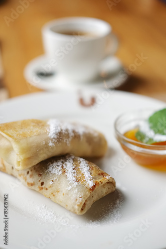 Soft focus photo of pancakes with jam and cup of coffee. Breakfast at a cafe?