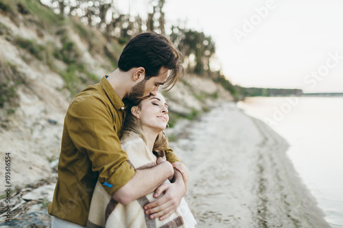 A beautiful couple is hugging and admires the sunset. Romantic date on the beach. Wedding. Artwork.