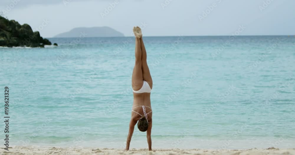 fitness woman standing on her hands on a tropical beach in the Caribbean fitness woman standing on her hands on a tropical beach in the Caribbean