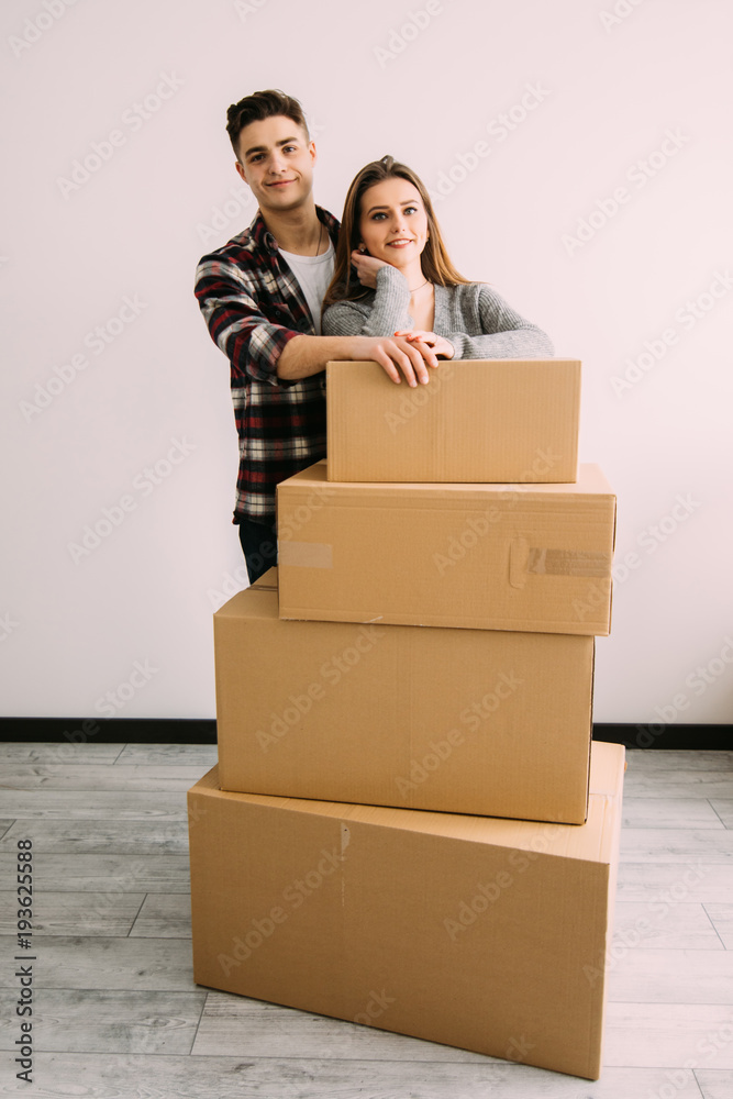 Happy couple standing near boxes in their new apartment. Relocation and moving. Happy couple standing near boxes in their new apartment. Relocation and moving.