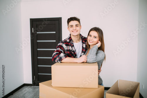 Smiling couple leaning on boxes in new home. Couple in new apparment after moving. photo