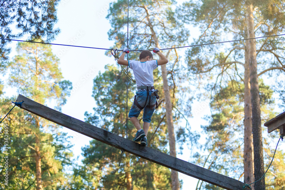 cute boy climbs on a very risky treetops in rope adventure park in the summer cute boy climbs on a very risky treetops in rope adventure park in the summer