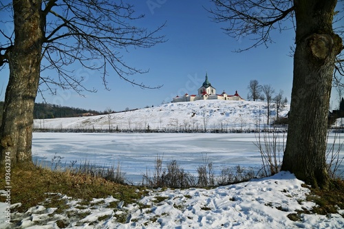 Winter scene with view of Pilgrimage Church of St John of Nepomuk at Zelena Hora hill over the pond during cold bright sunny day with clear blue sky in February