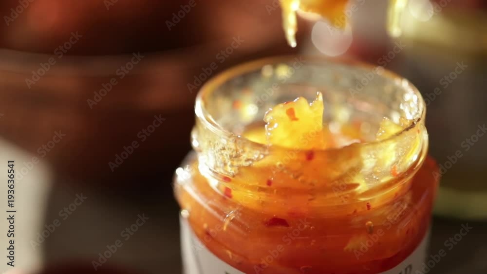 Close up, knife removes jam from jar