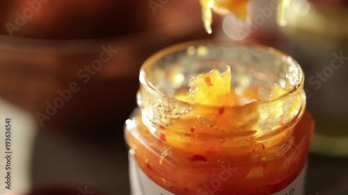 Close up, knife removes jam from jar photo