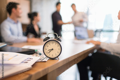 Vintage alarm clock in business office with blur business people working background.
