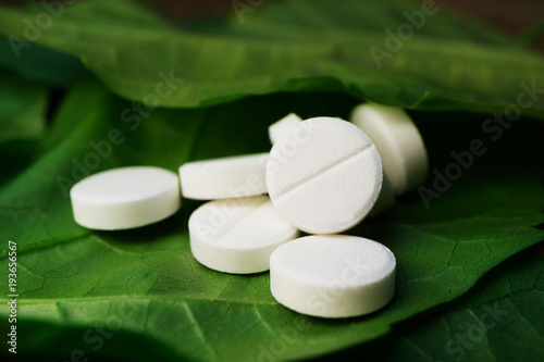 tablets lying in a large number among the green leaves, homeopathic medicines safe medicine by nature