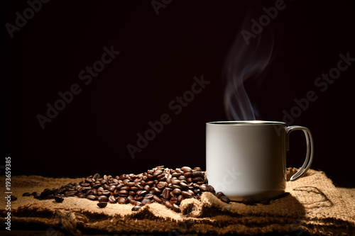 Filiżanka kawy z dymnymi i kawowymi fasolami na czarnym tle