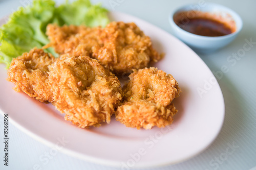 Thai fried shrimp cake on pink plate with sweet chili sauce.