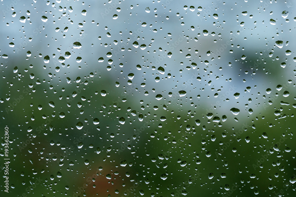 Rain droplets on a window with green background