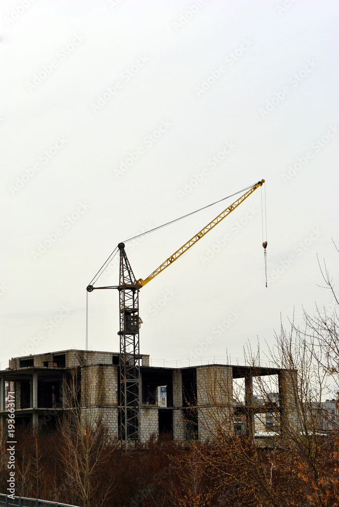 Mounting crane at construction of apartment building, cloudy autumn day