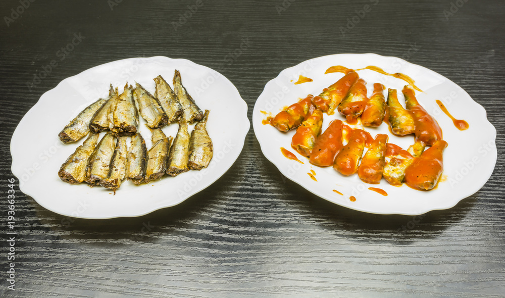 Plates with smoked sprats in oil and tomato sauce. Plates with smoked sprats in oil and tomato sauce.